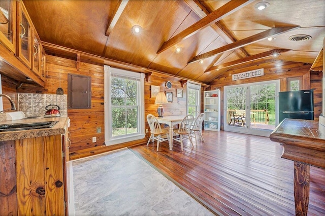 dining room featuring lofted ceiling with beams, wood walls, wooden ceiling, wood finished floors, and visible vents