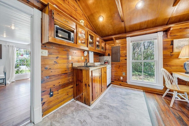 kitchen with wooden walls, a sink, stainless steel microwave, wooden ceiling, and electric panel