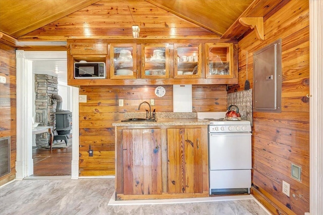 kitchen featuring a sink, white range oven, vaulted ceiling, and wood walls