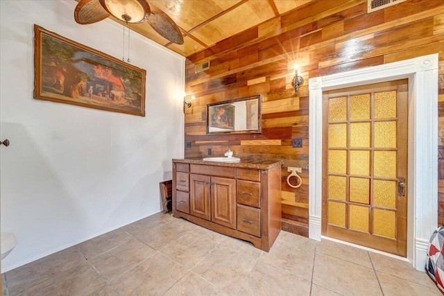 bathroom featuring vanity, wooden walls, wood ceiling, tile patterned floors, and a ceiling fan