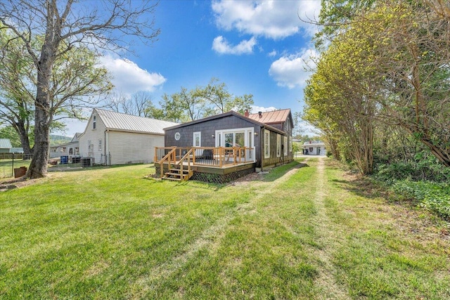 back of property featuring a standing seam roof, metal roof, a yard, and a deck