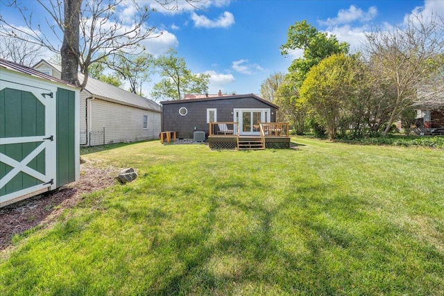 back of house featuring a lawn, a storage unit, an outbuilding, and a deck