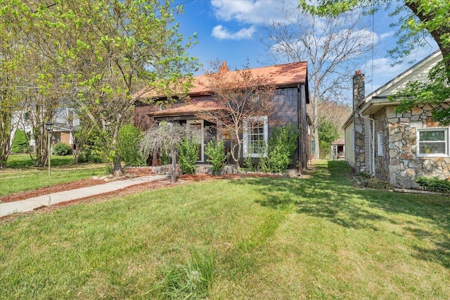 view of front of home featuring stone siding, a chimney, and a front yard