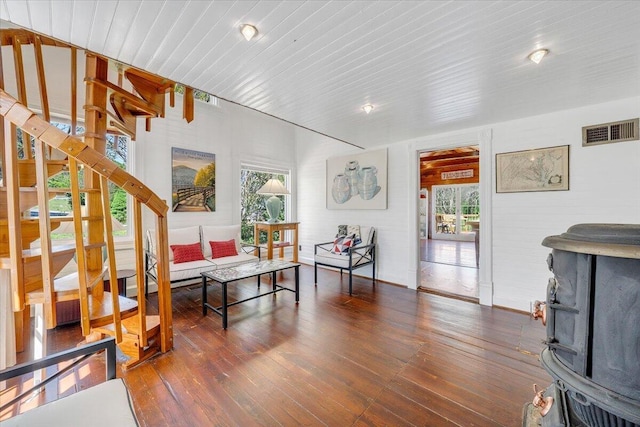 living room with hardwood / wood-style flooring, visible vents, wood ceiling, and a wood stove