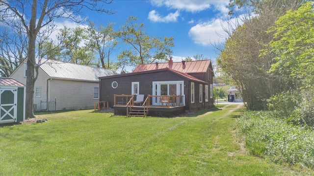 rear view of property featuring a storage unit, a wooden deck, an outbuilding, a yard, and metal roof
