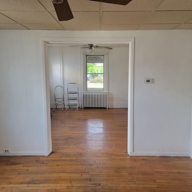 2118 Berkley Ave SW, Roanoke, VA 24015 - empty room with radiator heating unit, a drop ceiling, wood-type flooring, baseboards, and a decorative wall