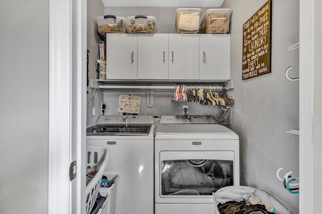clothes washing area featuring cabinet space and washing machine and dryer
