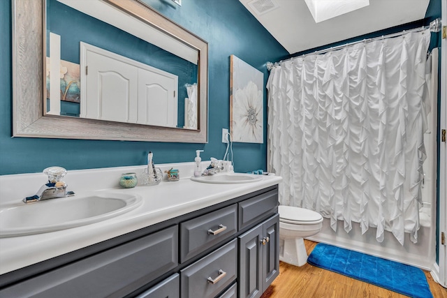 bathroom featuring a sink, double vanity, toilet, wood finished floors, and visible vents