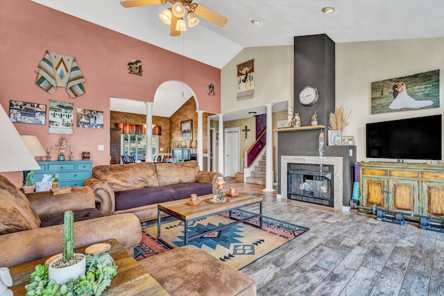 living room featuring wood finished floors, ceiling fan, high vaulted ceiling, ornate columns, and arched walkways
