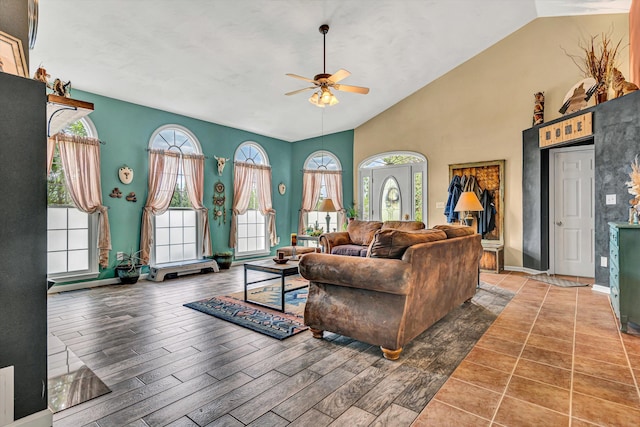 living area featuring baseboards, a ceiling fan, wood finished floors, and high vaulted ceiling