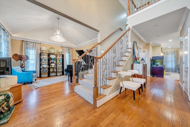 stairway with a chandelier, crown molding, wood finished floors, lofted ceiling, and baseboards