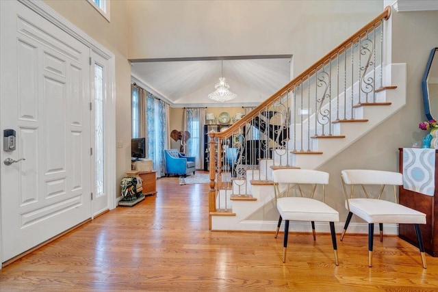 foyer featuring a chandelier, stairway, wood finished floors, baseboards, and a high ceiling