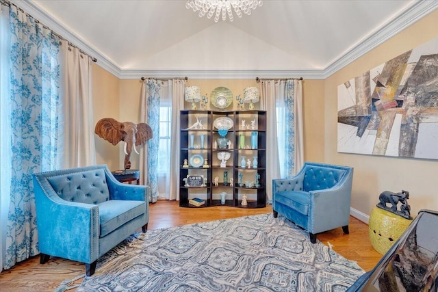 living area with ornamental molding, wood finished floors, a chandelier, baseboards, and vaulted ceiling