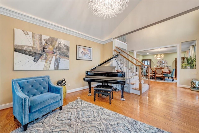 living area with a chandelier, stairway, wood finished floors, baseboards, and vaulted ceiling