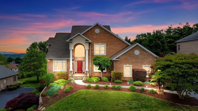 traditional-style home with brick siding and a front lawn