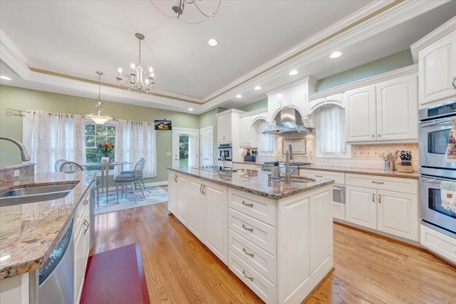 kitchen featuring a sink, appliances with stainless steel finishes, an island with sink, recessed lighting, and a chandelier