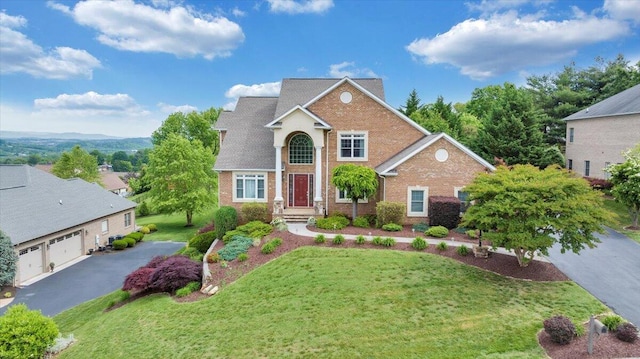 traditional-style home with brick siding, a front yard, a garage, and driveway