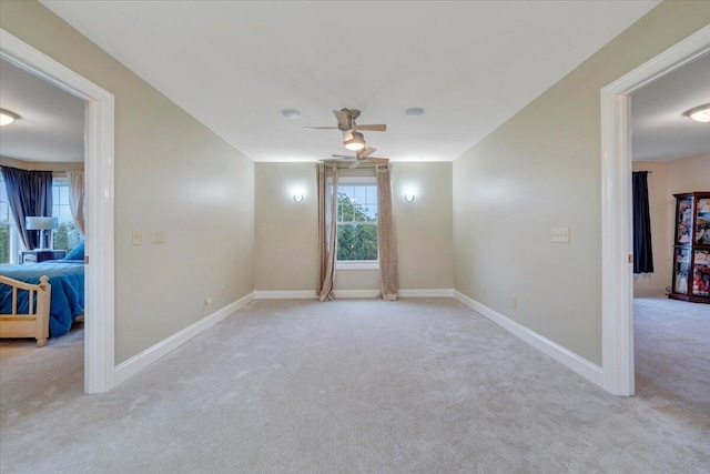 spare room featuring carpet floors, a ceiling fan, and baseboards