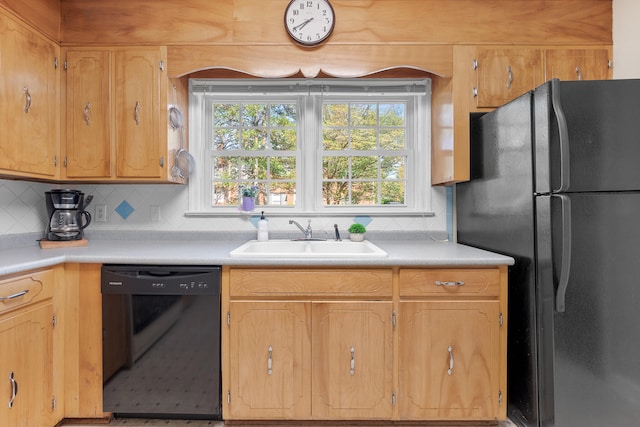 kitchen with a sink, light countertops, tasteful backsplash, and black appliances