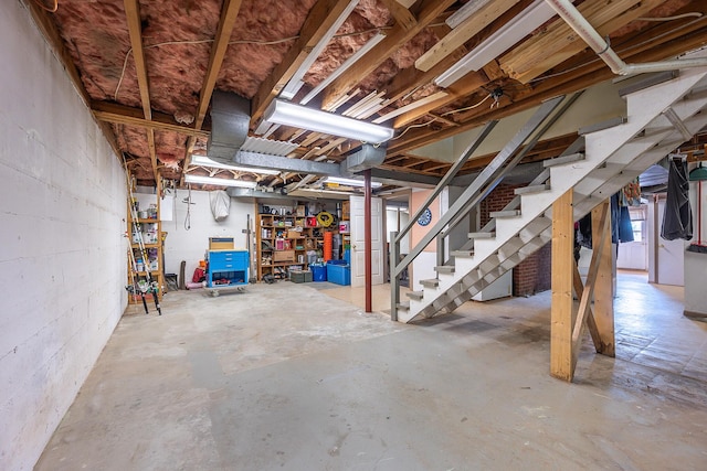 unfinished basement with stairs and concrete block wall