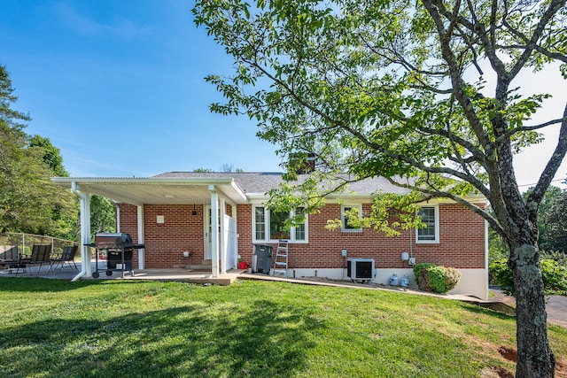 back of house featuring brick siding, a chimney, central air condition unit, a patio, and a yard
