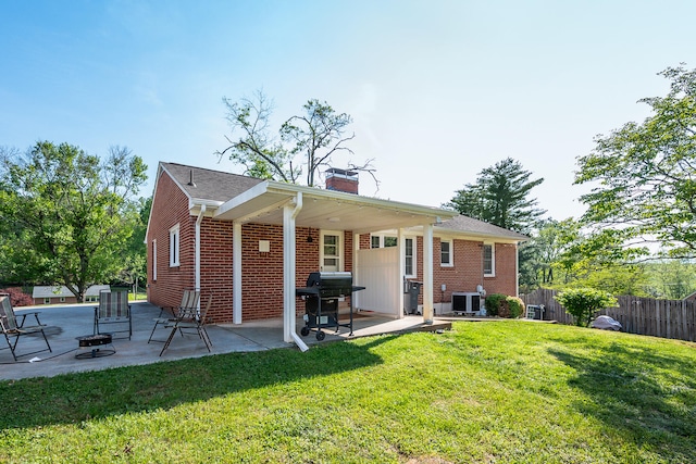 rear view of house with fence, central AC unit, a chimney, a lawn, and a patio