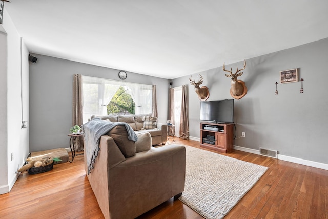 living area featuring visible vents, baseboards, and wood finished floors