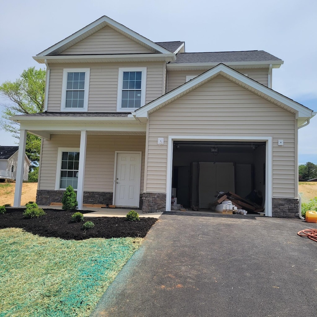 view of front of house featuring a porch, a shingled roof, driveway, and stone siding