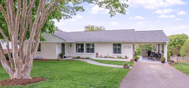 ranch-style home featuring a shingled roof, a front lawn, aphalt driveway, and fence