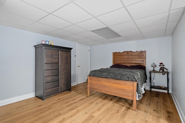 finished below grade area featuring baseboards, light wood-type flooring, stairs, and a paneled ceiling