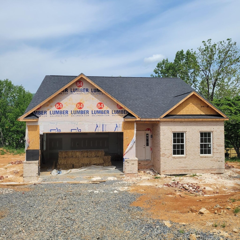 unfinished property with a shingled roof and brick siding
