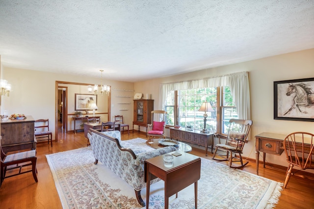 living room featuring a textured ceiling, a chandelier, and wood finished floors