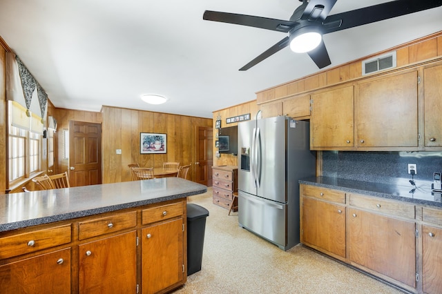 kitchen featuring visible vents, wood walls, dark countertops, and stainless steel fridge with ice dispenser