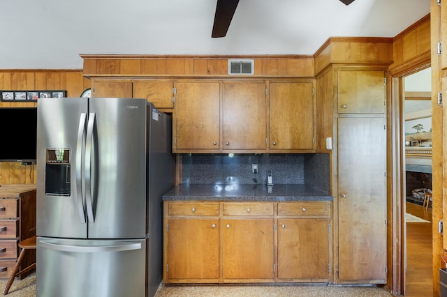 kitchen with a ceiling fan, stainless steel refrigerator with ice dispenser, visible vents, tasteful backsplash, and brown cabinets