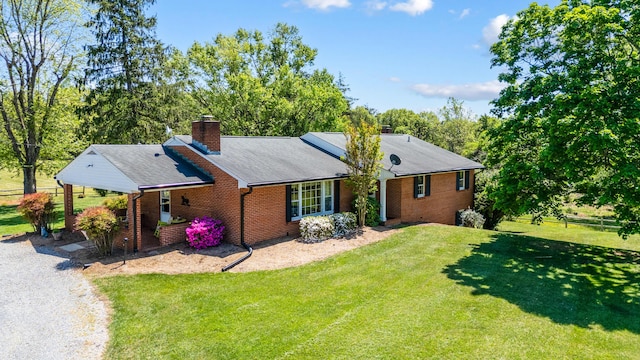 view of front of home with brick siding, roof with shingles, a chimney, and a front yard
