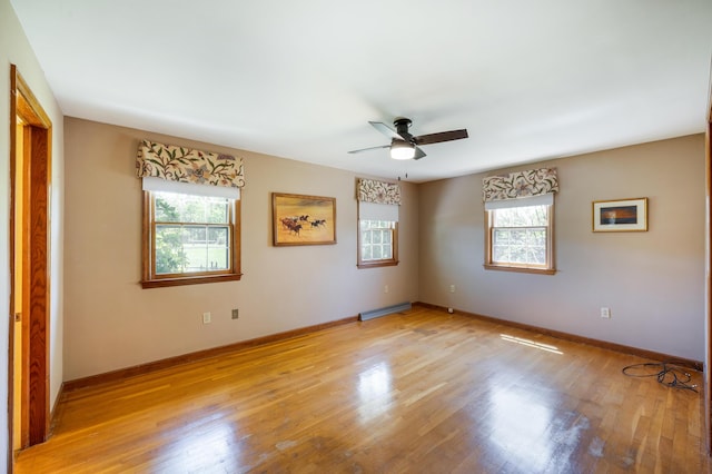 spare room with baseboards, ceiling fan, and light wood-type flooring