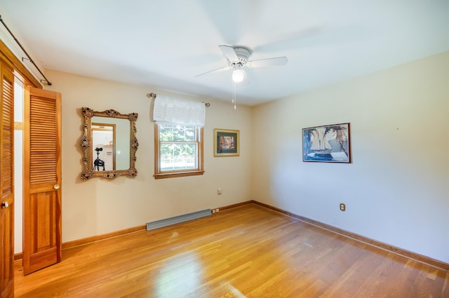 spare room featuring light wood-style floors, baseboards, a baseboard radiator, and a ceiling fan