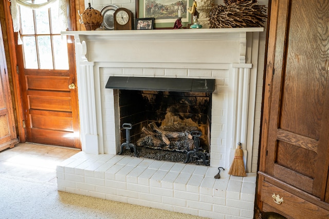 interior details featuring a brick fireplace and carpet