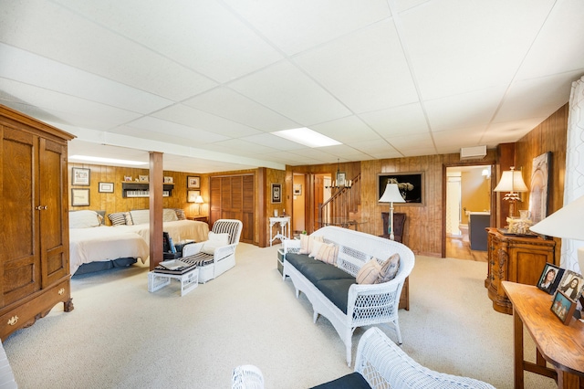 living room featuring wood walls, carpet, and a drop ceiling