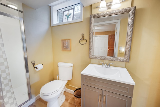 full bathroom featuring vanity, baseboards, a stall shower, and toilet