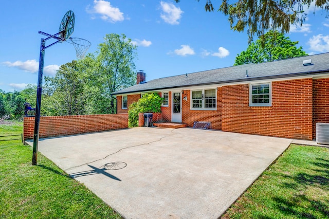 back of house with a chimney, brick siding, a patio area, central air condition unit, and a yard