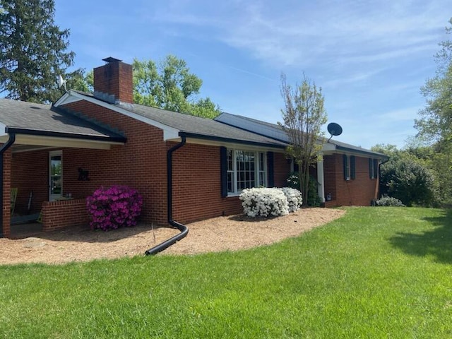 view of home's exterior with a yard, brick siding, a chimney, and roof mounted solar panels