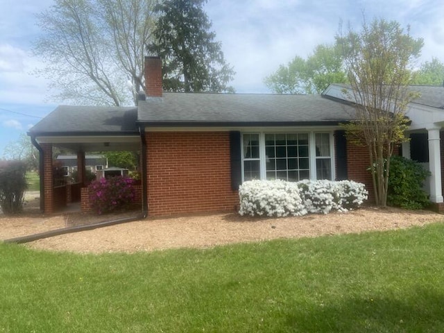 view of property exterior with brick siding, roof with shingles, a yard, and a chimney