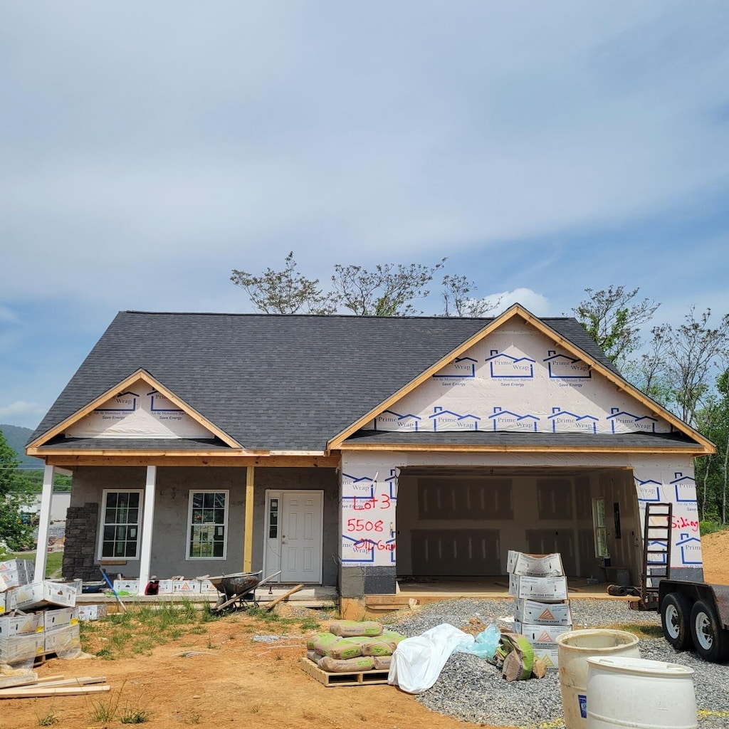 property under construction featuring roof with shingles and a garage