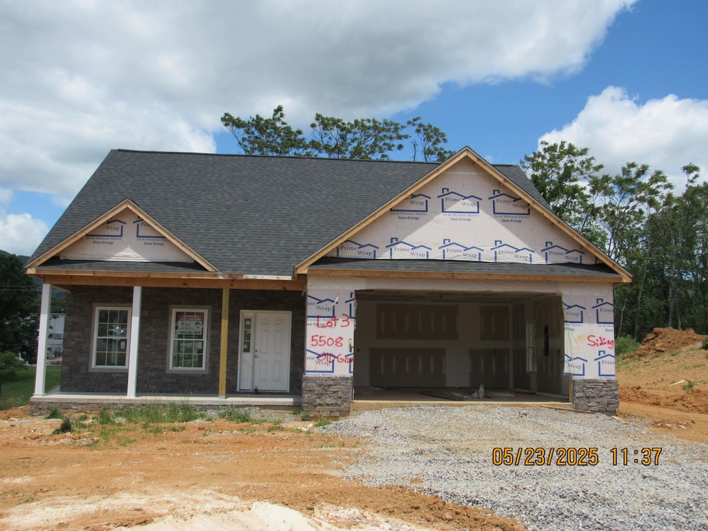 5598 Old Grove Ln, Salem, VA 24153 - property under construction featuring dirt driveway, covered porch, an attached garage, stone siding, and roof with shingles