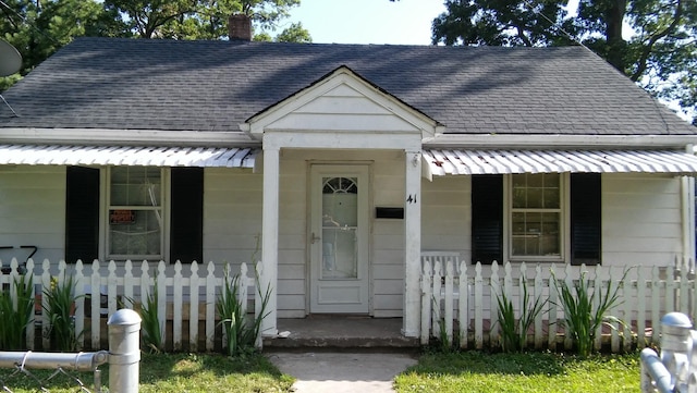 bungalow featuring a porch, fence, a chimney, and roof with shingles