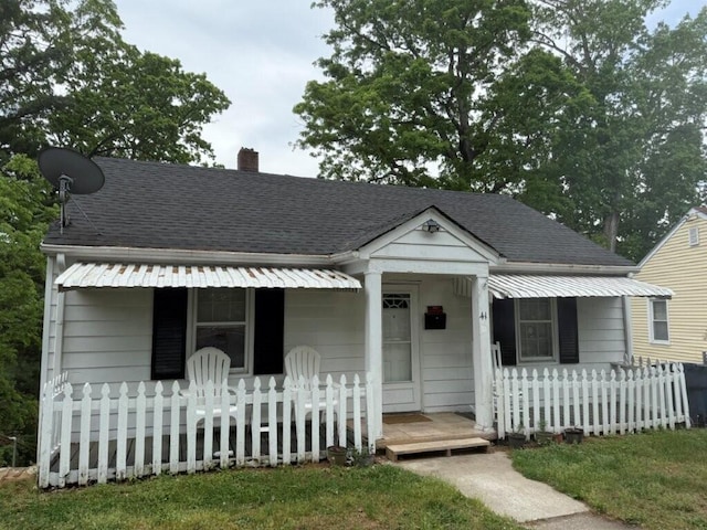 bungalow-style house featuring a porch, a chimney, fence private yard, and roof with shingles