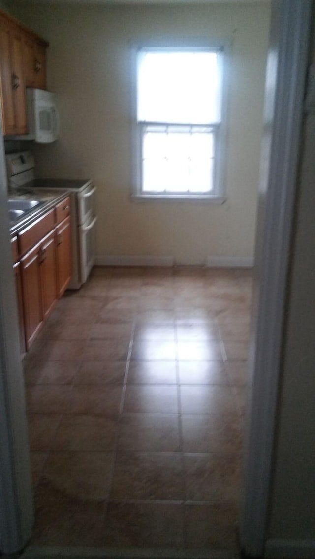kitchen featuring dark countertops, baseboards, white microwave, and electric range
