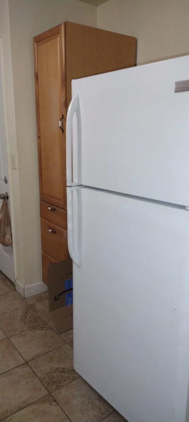 kitchen featuring freestanding refrigerator and light tile patterned flooring