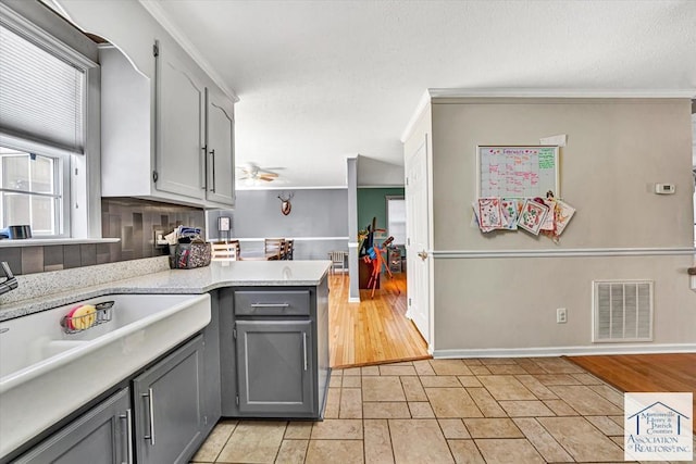 kitchen featuring a ceiling fan, visible vents, gray cabinetry, light countertops, and baseboards